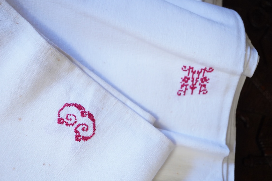 Six French provincial linen sheets each with a red cross stitched monogram to the turn back.